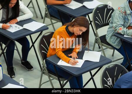 Focused high school girl student taking exam at desk in classroom Stock Photo