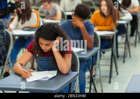 Focused high school girl student taking exam at desk in classroom Stock Photo