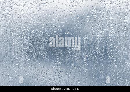 Raindrops, condensation on the glass window during heavy rain, water drops on blue glass Stock Photo