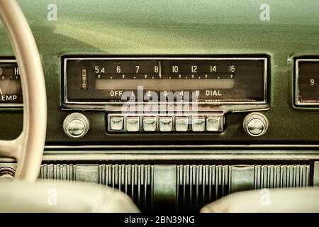 Retro styled image of an old car radio inside a green classic car Stock Photo
