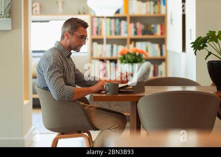 Businessman using digital tablet, working from home at dining table Stock Photo