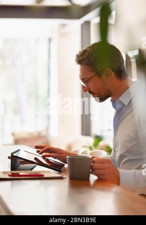 Businessman using digital tablet and drinking coffee, working from home Stock Photo
