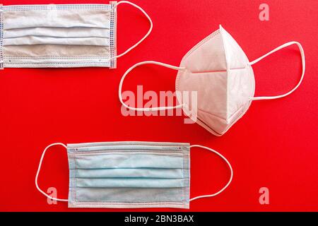 Set of different white face masks to prevent coronavirus in composition on a red cardboard Stock Photo