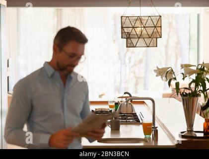 Businessman reading newspaper in morning kitchen Stock Photo
