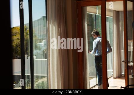 Businessman using smart phone at sunny window Stock Photo