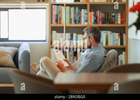 Man relaxing, reading book in living room Stock Photo