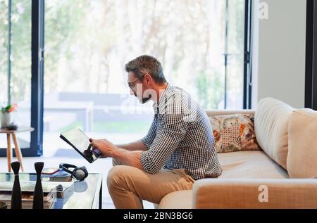 Man using digital tablet on living room sofa Stock Photo