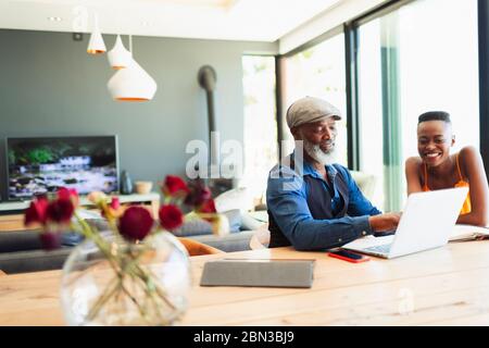 Father and daughter using laptop at dining table Stock Photo