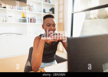 Smiling young woman working from home, using computer in home office Stock Photo