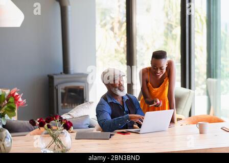 Father and daughter using laptop at dining table Stock Photo