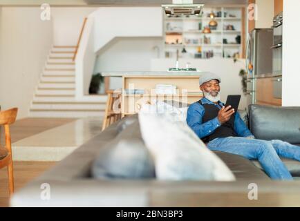 Man using digital tablet on living room sofa Stock Photo