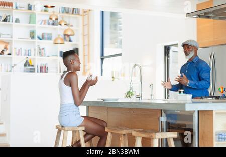 Father and daughter talking in modern kitchen Stock Photo