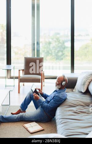 Man with headphones using digital tablet on living room floor Stock Photo