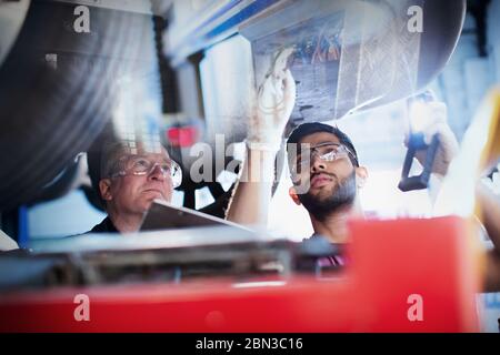 Male mechanics working under car in auto repair shop Stock Photo