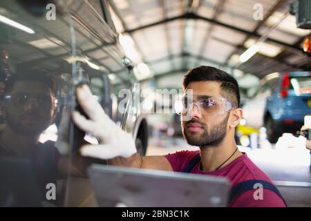 Focused male mechanic using digital tablet in auto repair shop Stock Photo
