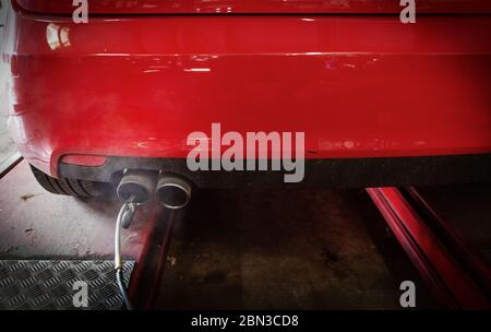 Equipment connected to exhaust pipe on car in auto repair shop Stock Photo