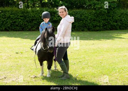 Dorney, Buckinghamshire, UK. 12th May, 2020. Sam and his Mum take out Shetland pony Diddy for a ride and so they all get their daily exercise during the Coronavirus Covid-19 Pandemic lockdown. Credit: Maureen McLean/Alamy Live News Stock Photo