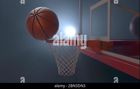 An action shot of a regular basketball teetering on the rim of a red basketball hoop dramatically spotlit from behind on an isolated dark background - Stock Photo