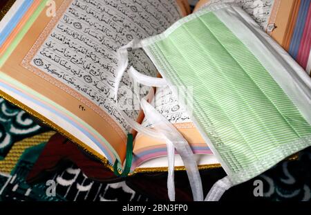 Religion and  coronavirus ( COVID-19). Quran and disposable surgical mask. Stock Photo