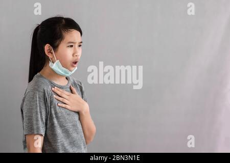Asia little girl wearing hygienic mask to prevent the virus, PM2.5, Coronavirus, (2019-nCoV). Asian little girl feeling unwell and coughing isolated o Stock Photo