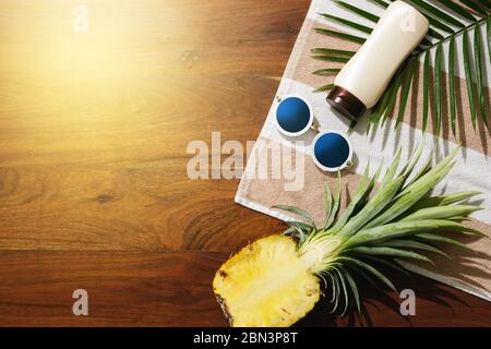 Different items for beach vacations. Sunscreen, sunglasses and pineapple fruit Stock Photo
