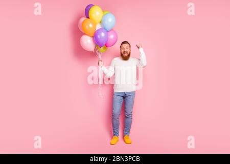 Full size photo positive guy hold helium balls baloons he get anniversary celebration his desire present raise fists scream yeah wear white jumper Stock Photo