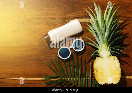 Different items for beach vacations. Sunscreen, sunglasses and pineapple fruit Stock Photo