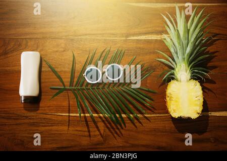 Different items for beach vacations. Sunscreen, sunglasses and pineapple fruit Stock Photo