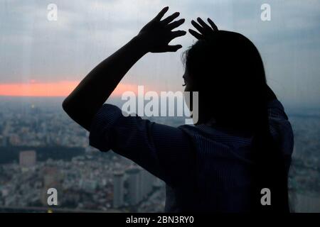 Silhouette of woman looking through the window.  Ho Chi Minh City. Vietnam. Stock Photo