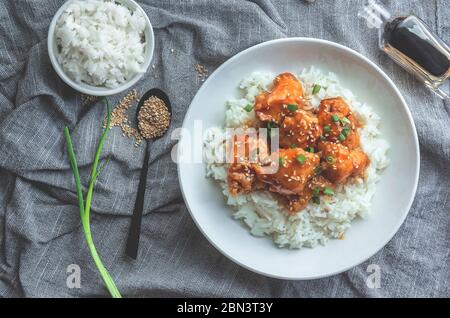 Delicious chicken with sweet and sour orange sauce accompanied by jasmine rice Chinese-style recipe, top view. Stock Photo