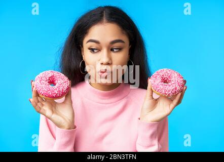 Thoughtful hungry woman choosing between donuts. Temptation food. Diet concept Stock Photo