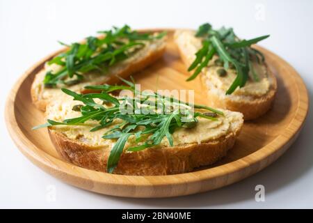 Sandwich of toasted bread slices with classic chickpea hummus spread, roasted pumpkin seeds and fresh arugula Stock Photo
