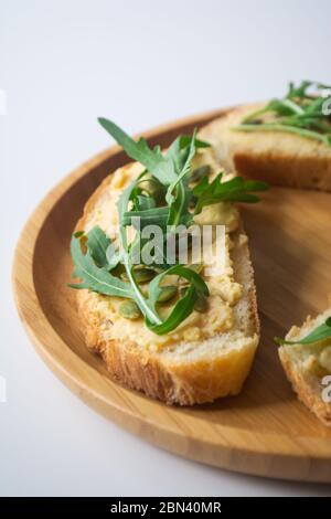 Sandwich of toasted bread slices with classic chickpea hummus spread, roasted pumpkin seeds and fresh arugula Stock Photo