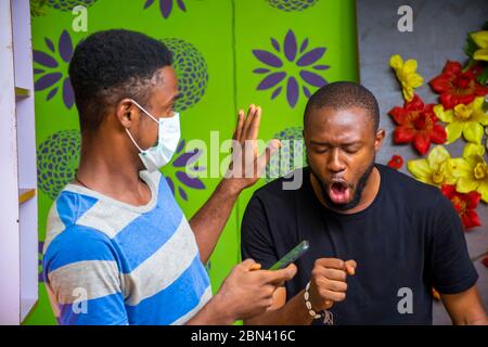 young black man wearing a nose mask to prevent himself from a pandemic and using his phone Stock Photo