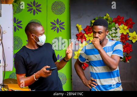 young black man wearing a nose mask to prevent himself from a pandemic and using his phone Stock Photo