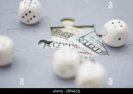 Rolling dice on Hundred dollar bills through the missing piece of jigsaw puzzles. Gambling concept. Stock Photo