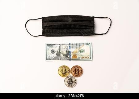 A few coins with a bitcoin sign dollar bill and black protective mask Stock Photo