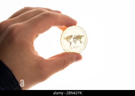 Male hand holds golden ripple coin isolated on white background Stock Photo