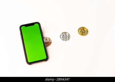 Bitcoin coins and phone with green screen on white background. Business, money, cryptocurrency concept Stock Photo