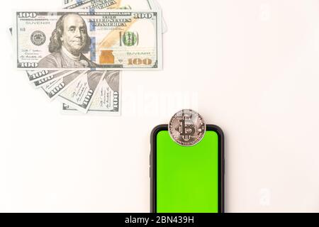 Coin crypto currency Bitcoin on the phone with green screen and dollar banknotes isolated on white Stock Photo