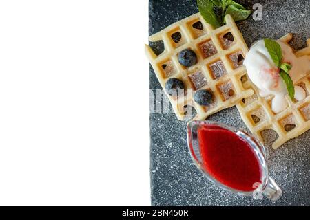 Fresh baked homemade classic Belgian waffles topped with icecream, fresh blueberries and mint isolated on white background, top down view. Savory Stock Photo