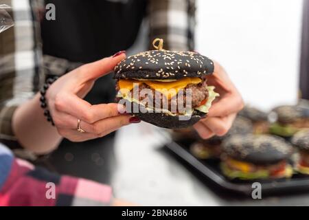 Close-up on an appetizing black burger in woman's hands Stock Photo