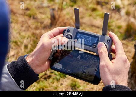 Close up mans hands holding a drones remote controller. A aerial shoot of a bridge is on the screen of smartphone. Real footage concept. Liberec Stock Photo