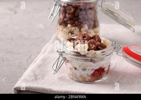 Granola crispy honey muesli with berries, cottage cheese and natural yogurt, located in two glass jars on a gray background, Horizontal format, Space Stock Photo