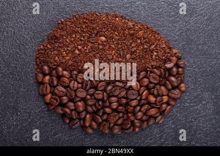 Freshly roasted ground coffee grains and whole grains lie on the table in the shape of a coffee grain. The concept of morning drink of aromatic coffee Stock Photo
