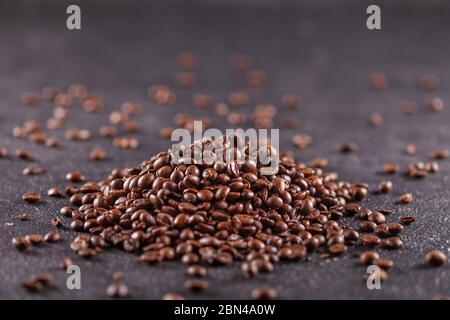 Freshly roasted aromatic coffee beans lie on a dark surface. Fresh morning fragrant drink concept Stock Photo