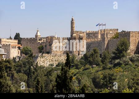 Jerusalem, Israel - May 5th, 2020: The old city of Jerusalem's walls with the tower of David and the flags of Israel and of the city of Jerusalem. Stock Photo