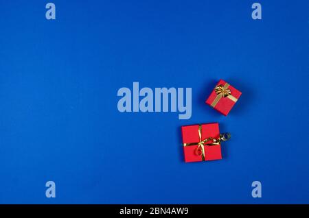 Two red gift boxes with golden ribbon on blue background. Top view, copy space, mock up, flat lay. Christmas, new year, Birthday, holiday. Festive bac Stock Photo
