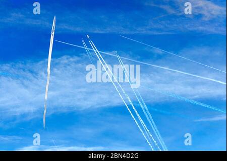 some crossing condensation trails of airplanes on the blue sky Stock Photo