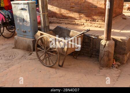 A construction iron cart for transportation of goods stands near a brick wall on a street in Kathmandu, Nepal. Stock Photo
